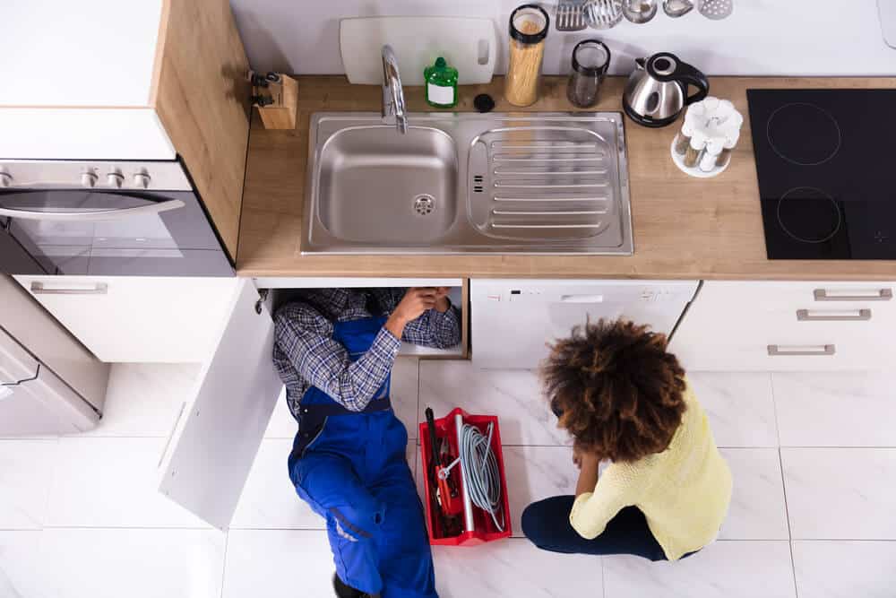 plumber helps woman fix her kitchen sink